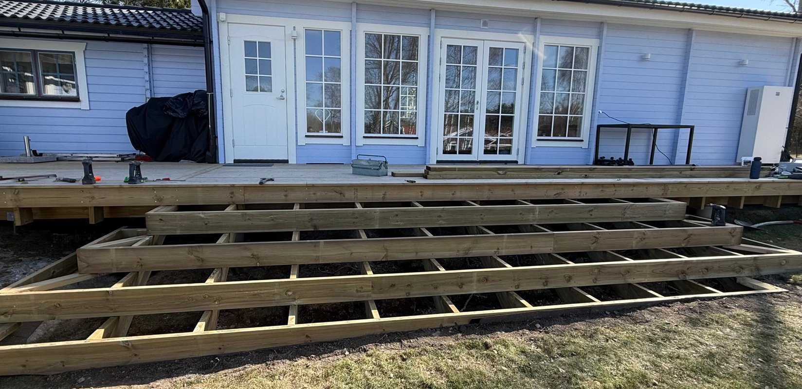 Altanrenovering med ny trästomme och trall framför hus