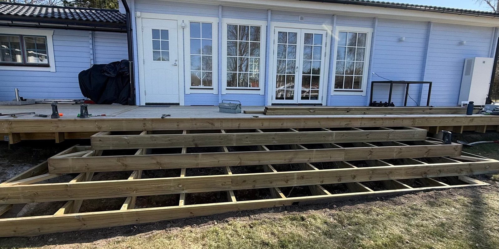 Altanrenovering med ny trästomme och trall framför hus