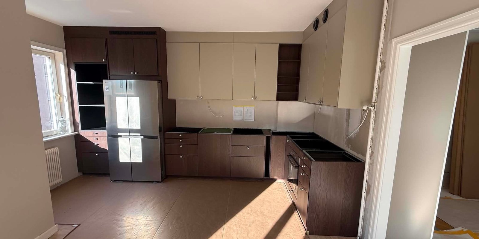 Köksrenovering i Södertälje under montering med mörka ekluckor och beige överskåp