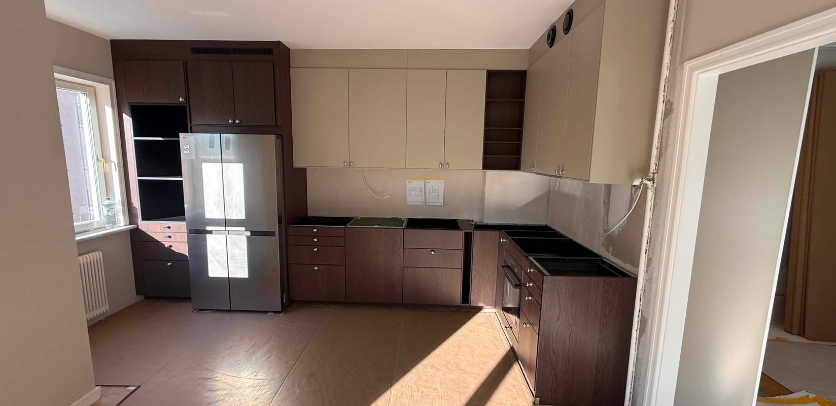 Köksrenovering i Södertälje under montering med mörka ekluckor och beige överskåp